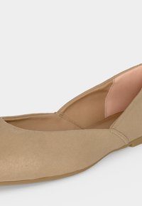 Μπέζ γυναικείο επίπεδο παπούτσι με στρογγυλεμένη μύτη και χαμηλά πλαϊνά, με μαλακή υφασμάτινη επένδυση και λεπτή λαστιχένια σόλα.