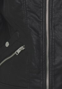 Giubbotto in finta pelle nera con cerniere argentate, superficie testurizzata e tasche laterali con zip. Forma sagomata e dettagli di cucitura visibili.