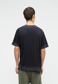T-shirt de algodão azul escuro com mangas curtas e gola redonda. Textura suave, design simples, sem padrões ou detalhes visíveis.