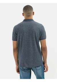 Granatowa koszulka polo z krótkim rękawem o teksturowanej tkaninie, z kołnierzykiem i prostym dołem, w połączeniu z jasnoniebieskimi dżinsami.