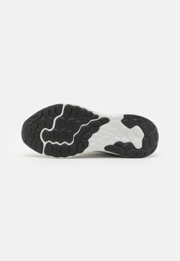 Suela de una zapatilla deportiva en blanco y negro con patrones de banda de rodadura texturizados y segmentados diseñados para ofrecer tracción.