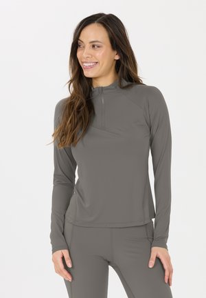 Grå langærmet atletisk top med en kvart lynlås, tætsiddende design, glat tekstur og syningdetaljer, parret med grå leggings.