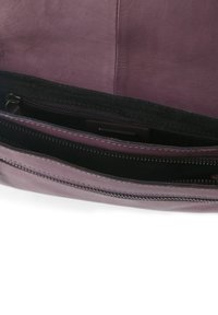 Interno di una borsa a tracolla in pelle viola con una texture liscia, dotata di più scomparti con zip e una fodera di tessuto scuro.