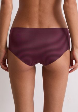Woman wearing purple and black horizontal striped hipster underwear, shown from the lower back to upper thighs against a plain background.