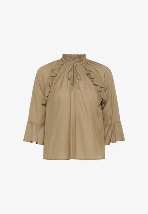 Blouse beige à manches longues avec détails volantés sur les épaules, un col montant froncé avec lien à nouer, et des poignets évasés.