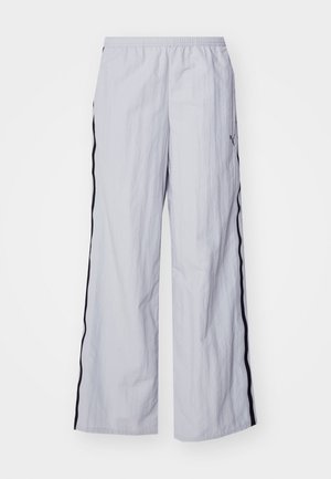 Pantalons large gris clair avec une finition texturée, présentant des rayures noires sur les côtés et une taille élastique pour le confort.