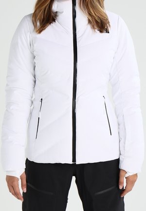 Weiße isolierte Jacke mit Reißverschluss, zwei schwarzen Reißverschlusstaschen und einem hohen Kragen. Das Design mit Paneelen verleiht der Jacke Struktur und Detail.