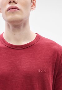 Κόκκινο T-shirt BOSS με στρογγυλή λαιμόκοψη, κατασκευασμένο από υφασμάτινο υλικό με υφή και μικρό λογότυπο στην αρι�στερή πλευρά του στήθους.