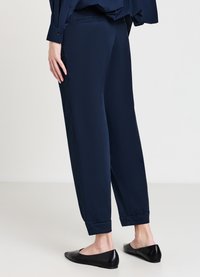 Pantaloni leggeri di colore blu navy con vestibilità rilassata, orli a risvolto e tasche laterali. Abbinati a scarpe nere basse.