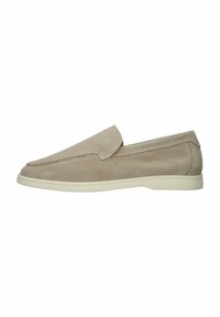 Zapato slip-on de ante beige con puntera redondeada y suela de goma blanca baja; presenta detalles de costura y una textura suave.