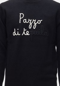 Maglione nero con collo e polsini a coste. Presenta un ricamo in bianco e blu scuro con la scritta "Pazzo di tequila." Texture morbida.