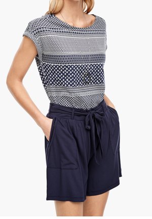 Granatowa bluzka w geometryczny wzór o luźnym kroju. Połączona z ciemnoniebieskimi szortami z wiązaniem w pasie i przednimi kieszeniami.
