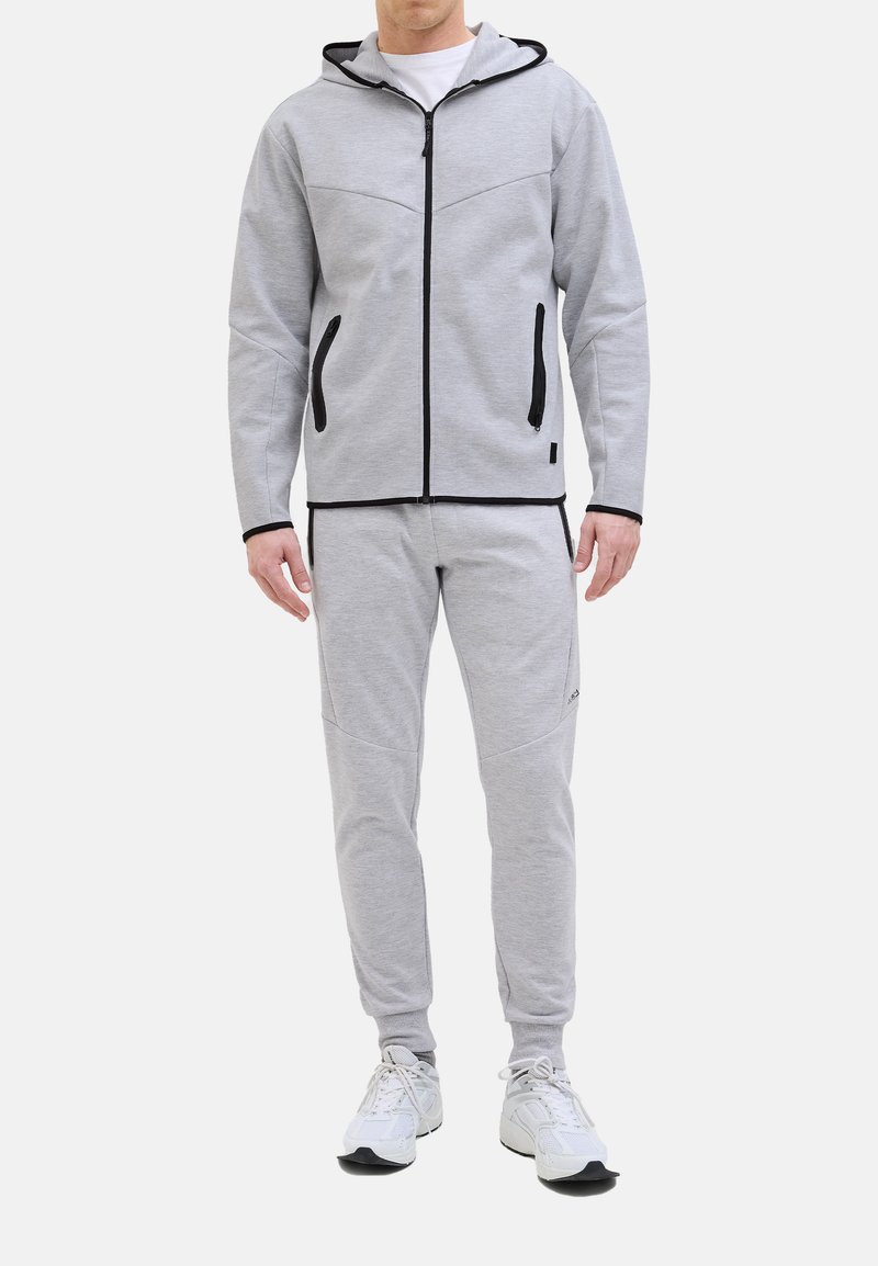 Grauer Reißverschluss-Hoodie mit Kapuze, schwarzen Akzenten und seitlichen Taschen, kombiniert mit passenden grauen Jogginghosen mit schmaler Passform und dezenter Logodetail.