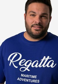 Modré bavlněné tričko s kulatým výstřihem a bílým textem: "Regatta" a "MARITIME ADVENTURES." Jednoduchý, neformální design bez vzorů.