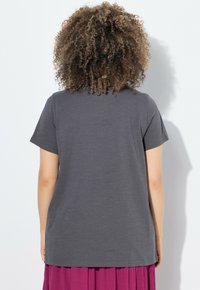 Grijze t-shirt met korte mouwen, zachte textuur, relaxte pasvorm, ronde halslijn, zoom zit op heuphoogte, gecombineerd met een geplooide paarse rok.