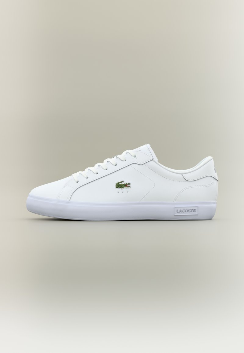 Λευκά δερμάτινα sneakers με μινιμαλιστικό σχεδιασμό, πράσινο κεντημένο λογότυπο, διάτρητες λεπτομέρειες και λευκή καουτσούκ σόλα.