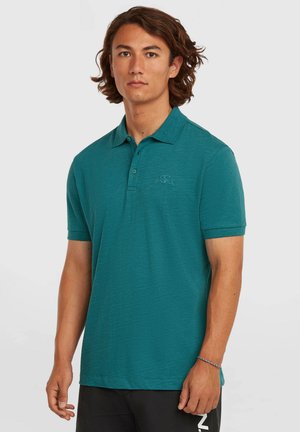 Moderena turkizna polo majica iz teksturirane tkanine, z klasičnim ovratnikom, tri gumbi na sprednji strani in vezenim logotipom na levi strani prsnega koša.