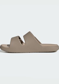 Beige slide sandal lavet af blødt, struktureret materiale. Har to brede, åbne stropper og en robust, rillet sål for greb.