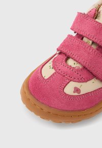 Ροζ σουέτ παπούτσι με διπλές λουρίδες βέλκρο, με μπεζ πάτο διακοσμημένο με μικρά λουλουδένια σχέδια και ελαστική σόλα.