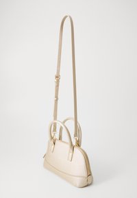 Sac à main beige avec une finition texturée, deux poignées supérieures et une bandoulière amovible et réglable. Présente une fermeture zippée et des détails en métal doré.