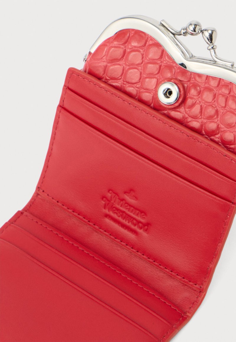 Red leather wallet with a textured interior, silver clasp, multiple card slots, and embossed branding. Smooth and structured design.