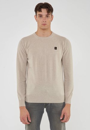 Maglione lavorato a maglia color beige chiaro con maniche lunghe, scollatura rotonda, polsini e orlo a coste, con un piccolo logo nero sul petto.