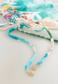 Farverige blomsterremme med en glat tekstur; enderne har gyldne solvedhæng. Designet inkluderer turkis, pink og grønne accenter.