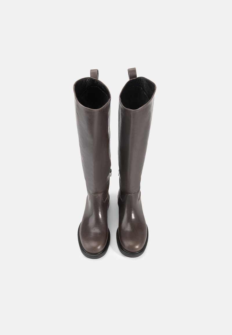 Bottes en cuir marron montant jusqu'au genou avec une texture lisse, bout rond et une tirette sur le col ; dotées d'une semelle plate en caoutchouc.