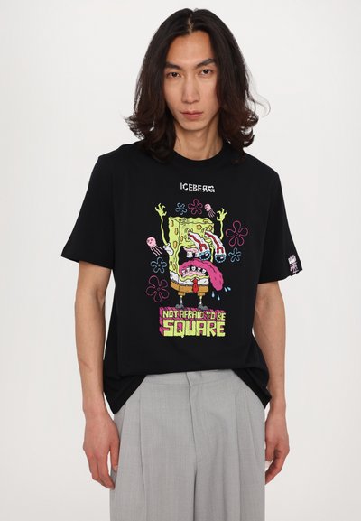 Black short-sleeve T-shirt featuring a colorful SpongeBob graphic with text "NOT AFRAID TO BE SQUARE," made of cotton with a relaxed fit.