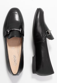 Svarta skinnloafers med fyrkantig tå, prydda med en dekorativ silverknäppning och en mjuk, vadderad innersula med perforeringar för andningsförmåga.