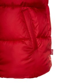 Rød pufferjakke med en glat, skinnende overflade, horisontal quiltet design og en sidelomme med rødt mærketag.