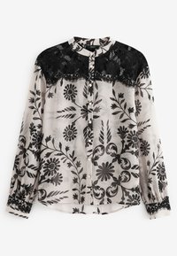Durchsichtige Bluse mit schwarzen Blumenmustern auf einem hellen Hintergrund, mit schwarzem Spitzenbesatz, Knopfverschluss und langen, gerafften Ärmeln.