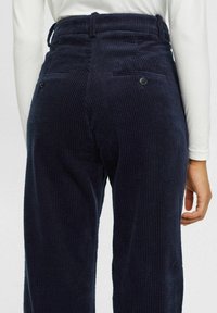 Navy rurki z korduroy z teksturowanym prążkowanym wzorem, dwiema tylnymi kieszeniami z dopasowanymi guzikami oraz elastyczną, marszczoną talią.