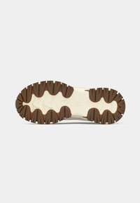 Εξωτερική σόλα παπουτσιού με υφασμένη επιφάνεια από καουτσούκ, με βαθιά αυλάκια σε καφέ χρώμα. Η μεσαία σόλα είναι ανοιχτόχρωμη με ομαλή υφή και λεπτομέρειες λογοτύπου.