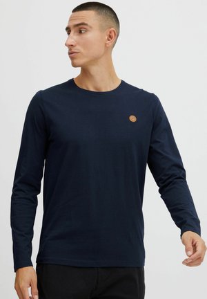 Navy long-sleeve T-shirt made of soft cotton, featuring a round neckline and a small circular logo on the left chest.