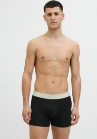 Schwarze Boxershorts mit einem weichen, hellgrauen Bund, der das Branding "JACK & JONES" trägt. Der Stoff wirkt glatt und eng anliegend.