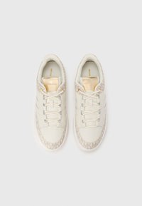 Hvide lædersneakers med lysebrune mønstrede detaljer, flade såler og guldbranding på tungen. Snørebåndene er trådet gennem huller.