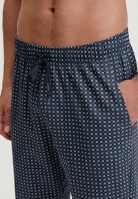 Pantaloni da pigiama a fantasia navy con design geometrico, vita elastica, cordoncino e tasche laterali. Il tessuto sembra morbido e leggero.