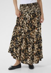Jupe maxi à imprimé léopard avec taille smockée, volants superposés et silhouette fluide ; les couleurs incluent le noir, le beige et le brun.