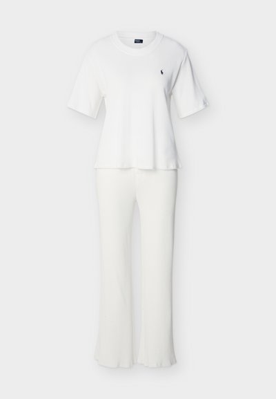 Λευκό κοντομάνικο ριμπ πλεκτό τοπ με στρογγυλή λαιμόκοψη και παντελόνι με φαρδιά πόδια, με μικρό σκουρόχρωμο κεντημένο λογότυπο στο στήθος.