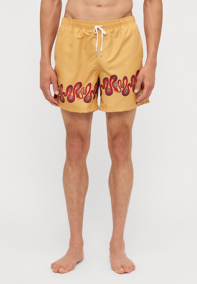 Gelbe Badehose mit einem wellenförmigen roten und schwarzen Muster am Saum. Verfügt über einen elastischen Bund und eine Kordel zum Verstellen.