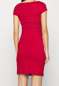 Röd figurnära klänning av stretchigt tyg, med korta ärmar och rund halsringning, slät textur och längd till mitten av låret.