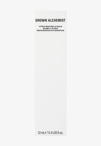 Witte rechthoekige verpakking met zwarte tekst. Bevat "Grown Alchemist Hydra-Restore Lip Balm," 12 mL formaat. Glad oppervlak, minimalistisch ontwerp.
