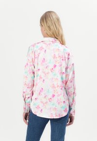 Camicia a maniche lunghe realizzata in tessuto morbido con un motivo floreale colorato nelle tonalità di rosa, blu e giallo. Presenta un colletto classico e polsini con bottoni.