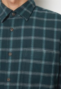 Zielona koszula flanelowa w kratę z kołnierzykiem na guziki, z białymi i jasnoniebieskimi liniami, kieszenią na piersi oraz brązowymi guzikami.