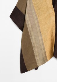 Brown, beige, and mustard striped fabric with textured and smooth sections hanging against a white background.