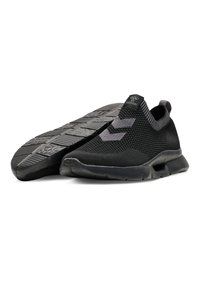 Black slip-on sneakers with a mesh upper, textured detailing, and a contrasting grey accent. Rubber sole with a patterned grip.