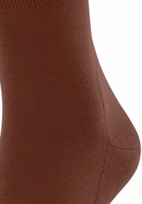 Chaussette en coton brun avec une texture lisse, une ouverture côtelée et une forme ajustée. Détail de surpiqûre notable sur le côté et couleur uniforme tout au long.