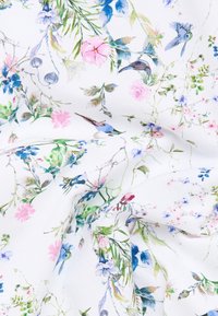 White fabric with a detailed floral and hummingbird pattern in soft blues, pinks, and greens, showing natural elements and delicate branches.