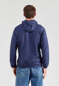 Giacca con cappuccio blu navy con polsini e orlo elasticizzati, realizzata in tessuto liscio, dal design casual adatta all'uso all'aperto.